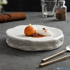 a white plate topped with food on top of a table next to utensils