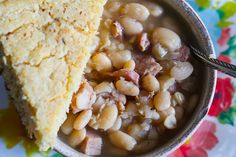 a bowl filled with beans next to a piece of pie on top of a plate