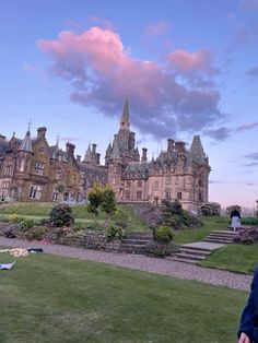 a man standing in front of a large building on top of a lush green field