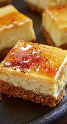 several pieces of dessert sitting on top of a black plate with brown sugar and caramel toppings