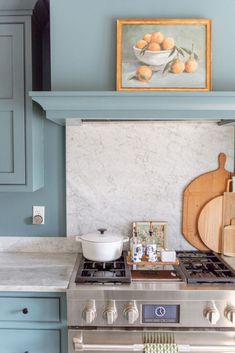 a stove top oven sitting inside of a kitchen next to a painting on the wall