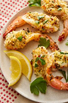 a white plate topped with shrimp next to lemon wedges