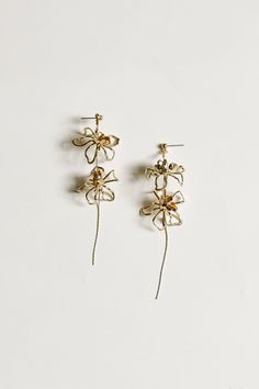 two pairs of gold earrings with flowers on them, one in the shape of a flower