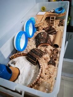 a toy train set in a plastic container filled with sand and dirt, including wooden toys