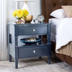 a night stand with two drawers and a clock on the side table next to it