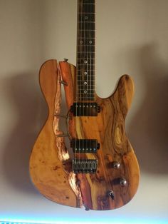 an electric guitar made out of wood and metal with strings attached to the neck, sitting on top of a shelf