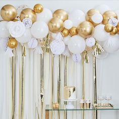 gold and white balloons are hanging from the ceiling