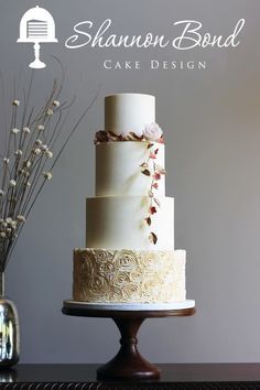 a three tiered cake sitting on top of a table next to a vase with flowers