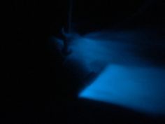 a dark room with blue light coming from the ceiling and on top of it is a bed