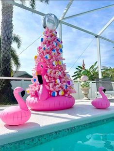 an inflatable pink christmas tree next to a pool with flamingos on it