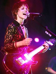 a woman singing into a microphone while holding a guitar