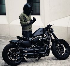 a man wearing a helmet standing next to a black motorcycle