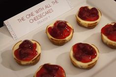 small pastries are arranged on a white tray with a sign in the background that says, the one with all the cheesecakes