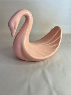 a pink swan shaped vase sitting on top of a white sheet