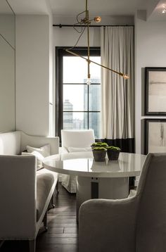 a living room filled with white furniture next to a large window covered in drapes