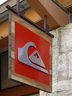 a red and silver sign hanging from the side of a building next to a brick wall