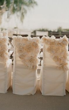 four white chairs with ruffled pillows on them