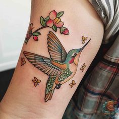 a hummingbird with flowers on its wings is shown in this tattoo design by the talented artist