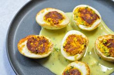 deviled eggs with green sauce on a black plate