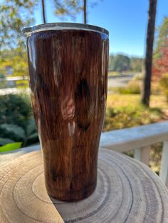 a wooden cup sitting on top of a table next to a tree stump in the sun