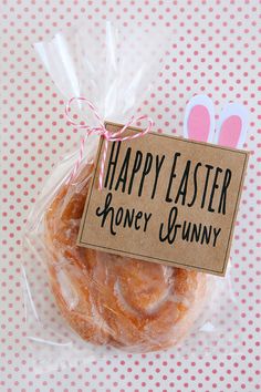 a bagel wrapped in plastic on top of a pink polka dot tablecloth with a sign that says happy easter honey bunny