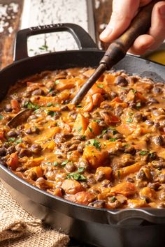 a person stirring beans in a skillet