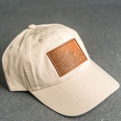 A floral stamped Leather Patch Unstructured Style Hat is the perfect gift for anyone who loves nature. All hats ship for free within the US! SPECS - Leather Patch Color Options: Natural Dublin, Nut Brown Dublin, or Cafe Chromexcel - Hat Color Options: Choose from Stone, Black, Navy, or Gray - All of our products are made to order by hand in McKinney, TX MATERIALS REAL HORWEEN LEATHER: Premium Full-Grain Leather. - Each patch is one-of-a-kind and made from part of a whole hide of leather. There w Hat Leather Patch, Hiking Apparel, Refillable Leather Journals, Patch Hats, Stamped Leather, Horween Leather, Hat Patches, Men Gifts, Panel Hat