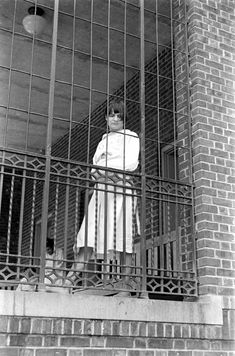 a man is standing behind bars in a jail cell