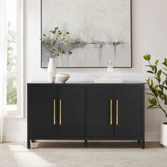 a black and gold sideboard with two vases on it in front of a large painting