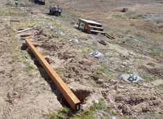 a wooden bench sitting in the middle of a field next to some dirt and trees