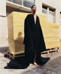 a woman is standing in front of a large stack of yellow boxes on the street