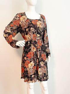 This is a floral dress from Carole Little.  The neutral colors make this perfect for fall.  The flowers are shades of rust, off white, gray and green all on a black background.  The front and back both have a flattering pleat design, with the front decorated with mother of pearl buttons.  Side zipper, no stretch.  No size tag.  Check measurements carefully. Length 37 inches Shoulder to shoulder 16 inches Sleeve 22 inches Underarm to underarm 42 inches Waist 34 inches Hips 46 Always happy to answer questions. All sales considered final unless item is grossly misrepresented. Thank you for shopping with us at We Wear Vintage! 01-2023-2 dk blue Fitted Floral Print Dress For Fall, Vintage Mini Dress With Buttons For Fall, Brown Floral Print Mini Dress For Fall, Vintage Long Sleeve Floral Dress, Vintage Floral Mini Dress For Fall, Vintage Floral Print Mini Dress For Fall, Grunge Mini Dress, Floral Short Dress, Floral Dresses Short