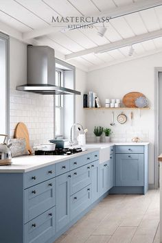 a kitchen with blue cabinets and white countertops is featured in this magazine, masterclasse kitchens