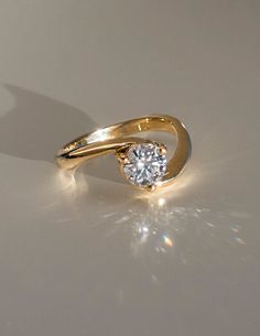 a yellow gold ring with a diamond on the top and bottom, sitting on a white surface