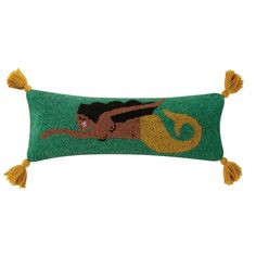 a green pillow with an image of a mermaid on the front and yellow tassels