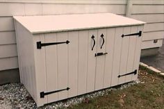 a white storage box sitting in the grass next to a building with black arrows on it