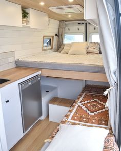 the interior of a camper with a bed, sink and dishwasher