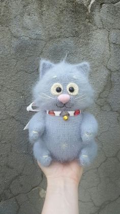 a hand holding a small blue cat toy