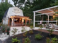 an outdoor restaurant with tables and chairs in front of it, surrounded by greenery