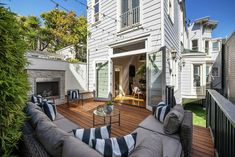 an outdoor living area with couches, table and fire place in front of the house