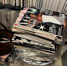 a stack of magazines sitting on top of a plastic bag next to a pile of books