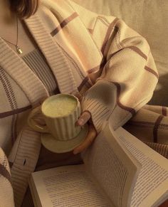 a woman holding a cup of coffee and an open book