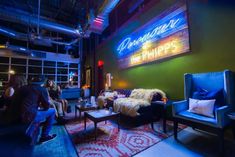 people are sitting around in a brightly lit room with neon signs on the walls and colorful rugs