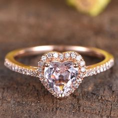 an engagement ring with a heart shaped pink diamond surrounded by small white and yellow diamonds