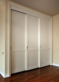 an empty room with white closet doors and hard wood flooring on the wooden floor