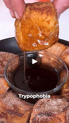 someone is dipping something into a bowl with chocolate sauce in it on top of some pastries