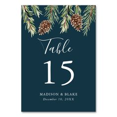 pine cones and evergreen branches are the centerpieces on this green table number card