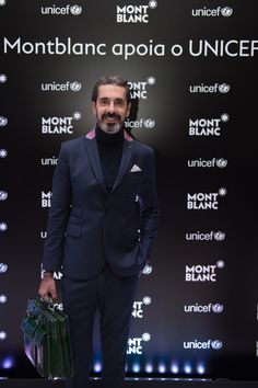 a man standing in front of a black backdrop holding a briefcase