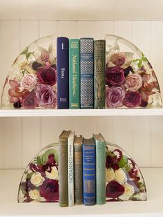 two shelves with books and flowers on them