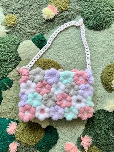 a handbag made out of crocheted yarn on a green rug with flowers